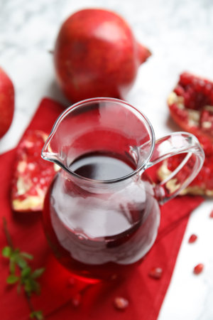 Pomegranate juice in jug and fresh fruits on white tableの写真素材