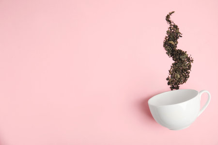 Dry tea brew and cup on pink background, flat lay. Space for textの写真素材
