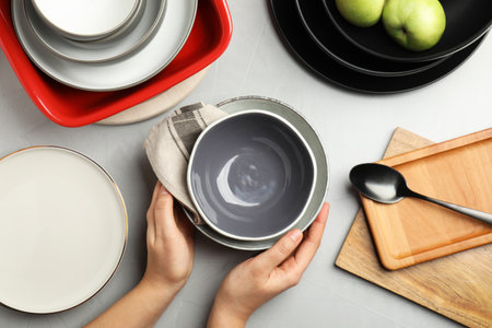 Woman with clean dishware at gray table, top viewの写真素材