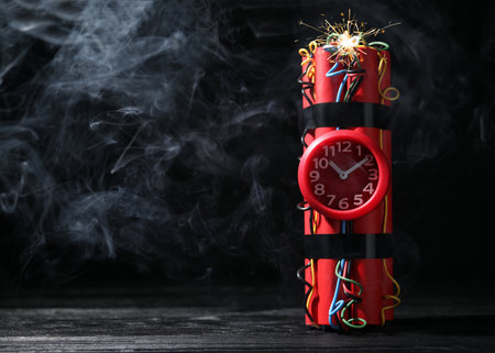 Dynamite time bomb on wooden table against black background. Space for textの写真素材