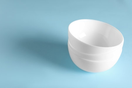 Empty ceramic bowls on light blue background. Space for textの写真素材