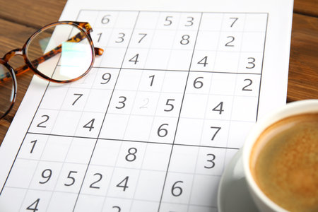 Sudoku, cup of coffee and eyeglasses on wooden table, closeupの写真素材