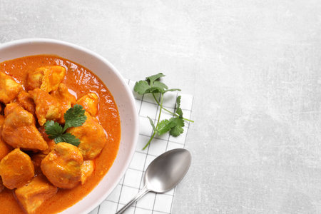 Bowl of delicious chicken curry on light gray table, top view. Space for textの写真素材