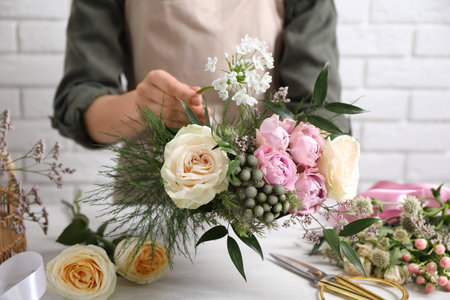 Florist making beautiful bouquet at white table, closeupの写真素材