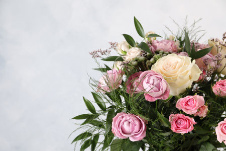 Beautiful bouquet with roses on light blue background, closeup. Space for textの写真素材