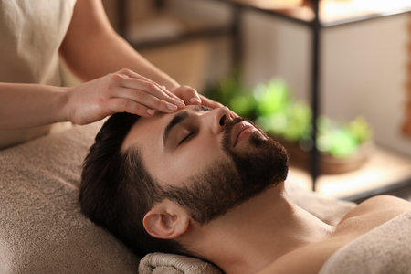 Young man receiving facial massage in beauty salonの写真素材