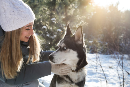 Young woman with dog in forest on winter day, space for textの写真素材