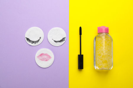 Dirty cotton pads, mascara and micellar cleansing water on color background, flat layの写真素材