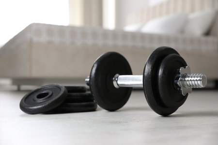 Steel dumbbell and weight plates on floor indoors. fitness at homeの写真素材