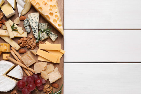 Cheese plate with grapes and nuts on white wooden table, top view. Space for textの写真素材