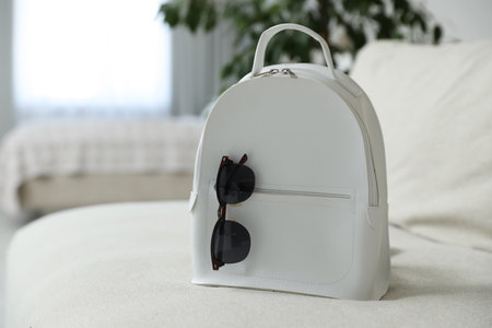 Stylish white backpack with sunglasses in living room, space for textの写真素材