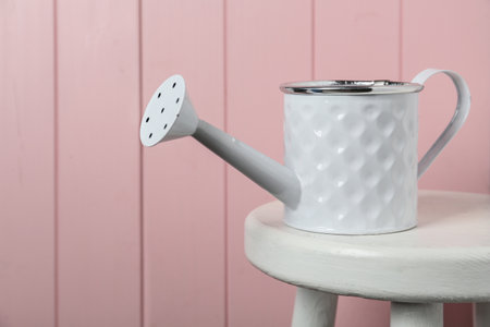 White metal watering can on table against pink wooden backgroundの写真素材