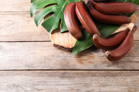 Delicious red baby bananas on wooden table, flat lay. Space for textの写真素材