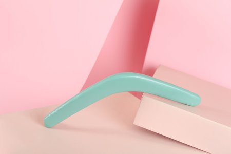 Creative composition with turquoise wooden boomerang on pink backgroundの写真素材