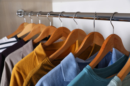Different stylish clothes hanging on rack in wardrobe, closeupの写真素材