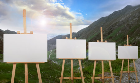 Wooden easels with blank canvases in mountains on sunny dayの写真素材