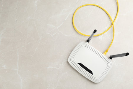 Modern WiFi router on light gray marble background, top view. Space for text