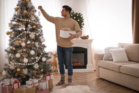 Man decorating Christmas tree in beautiful room interiorの写真素材