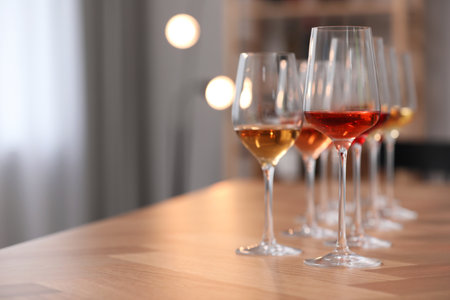 Different sorts of wine in glasses on wooden table indoors. Space for text