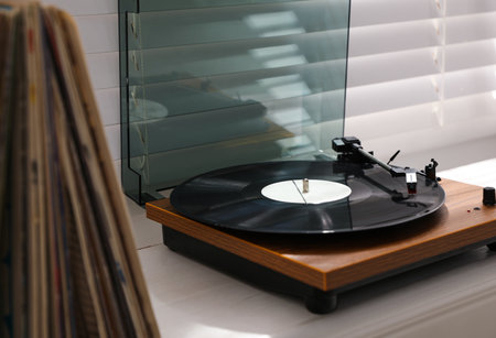 Stylish turntable with vinyl disc on windowsill in roomの写真素材