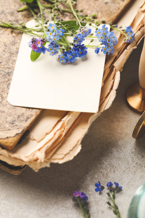 Beautiful Forget-me-not flowers and antique book on gray table, closeupの写真素材