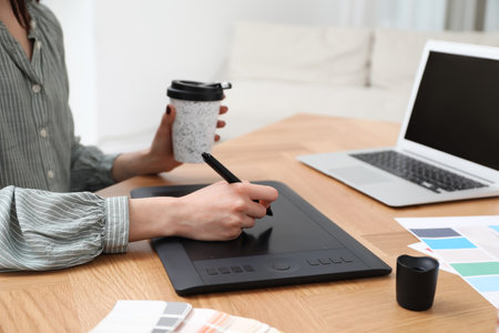 Professional designer with graphic tablet at wooden table, closeupの写真素材