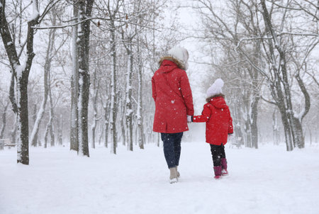 Mother with her child spending time outside on winter day, back view. christmas holidaysの写真素材