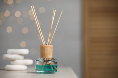 Aromatic reed air freshener and pebbles on wooden table. Space for text