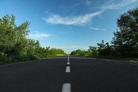Asphalt road running through countryside on sunny dayの写真素材