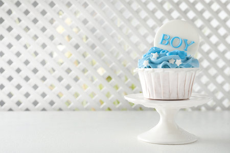 Delicious cupcake with light blue cream and Boy topper on white table, space for text. baby shower partyの写真素材