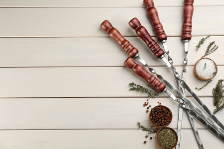 Flat lay composition with metal skewers on white wooden table. Space for textの写真素材