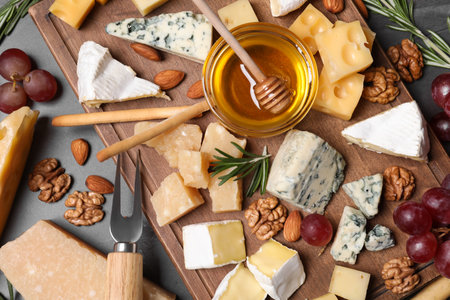 Cheese plate with honey, grapes and nuts on gray table, flat layの写真素材
