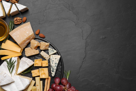 Cheese plate with honey, grapes and nuts on black table, flat lay. Space for textの写真素材