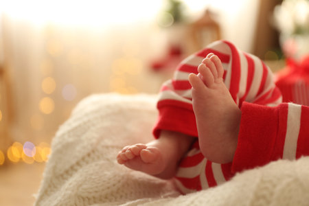 Cute little baby on knitted blanket in room against Christmas lights, closeup. Space for textの写真素材