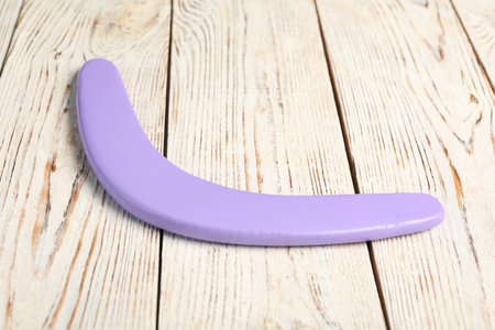 Purple boomerang on white wooden background. outdoor activitiesの写真素材