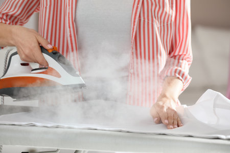 Young woman ironing clean laundry with steam, closeupの写真素材