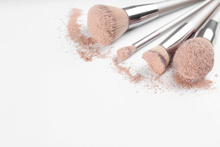 Different makeup brushes with crushed cosmetic product on light background, closeup. Space for textの写真素材