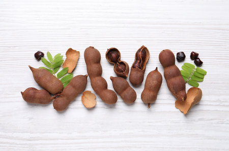 Delicious ripe tamarinds and leaves on white wooden table, flat layの写真素材