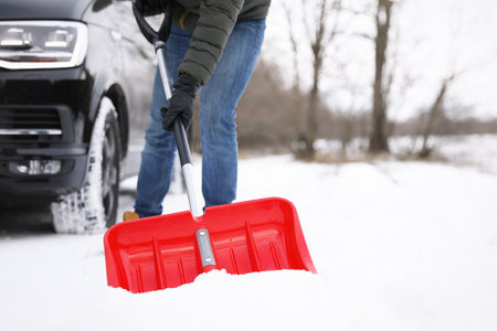 Man removing snow with shovel near car outdoors on winter day, closeupの写真素材