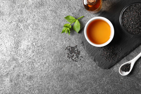 Black sesame seeds and oil on gray table, flat lay. Space for textの写真素材