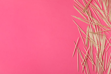 Wooden toothpicks on pink background, flat lay. Space for textの写真素材