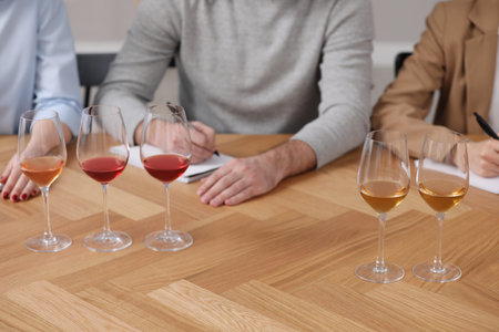 Different sorts of wine in glasses prepared for tasting and sommeliers at wooden table indoors, closeupの写真素材