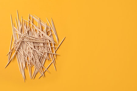 Wooden toothpicks on orange background, flat lay. Space for textの写真素材