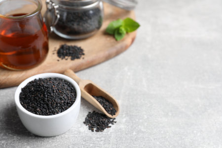 Black sesame seeds and oil on gray table, space for textの写真素材
