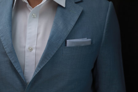 Man with handkerchief in suit pocket on black background, closeupの写真素材