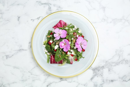 Fresh spring salad with flowers on white marble table, top viewの写真素材