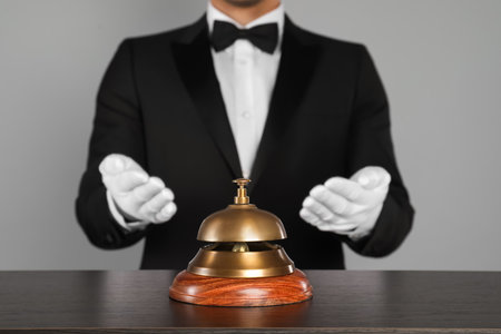 Butler at desk with service bell on gray background, closeupの写真素材