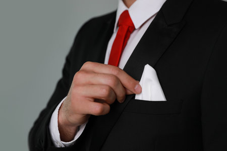 Man taking handkerchief from suit pocket on gray background, closeupの写真素材