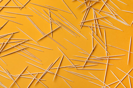 Wooden toothpicks on orange background, flat layの写真素材