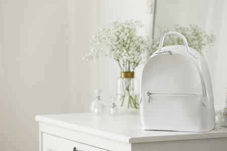 Stylish white backpack on chest of drawers indoors, space for textの写真素材